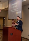 Deputy Under Secretary of the Navy (Policy) Advisor for International Affairs Phillip DeWolf delivers opening remarks at the NCIS Multiple Threat Alert Center Force Protection Intelligence Conference Nov. 19, 2024, at NCIS Headquarters.