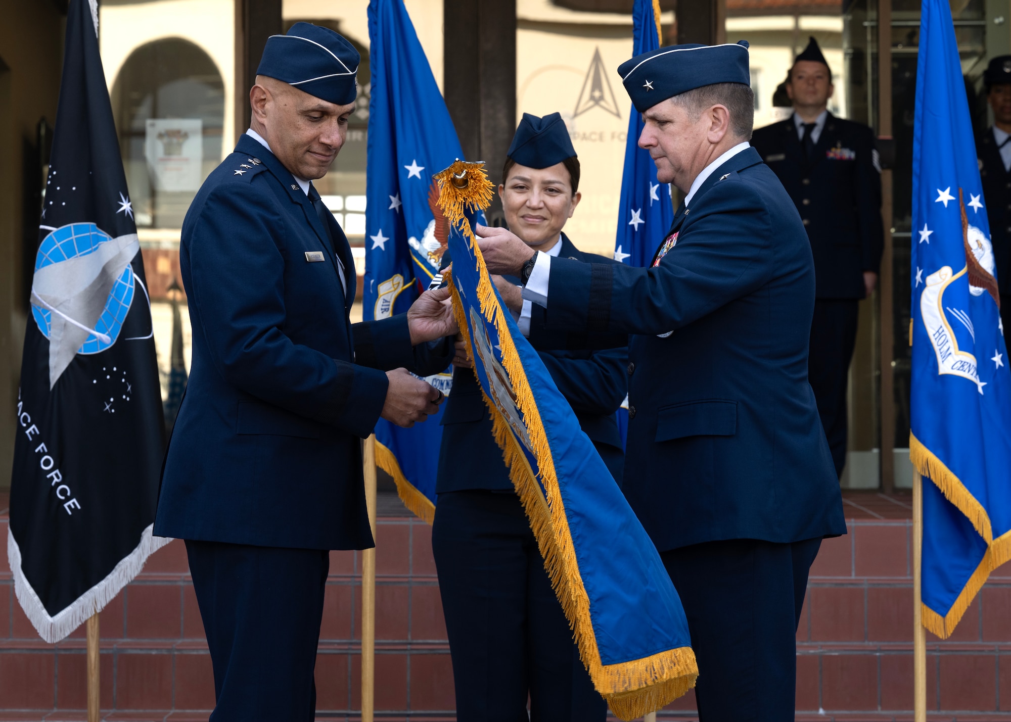 U.S. Air Force Lt. Gen. Brian Robinson (left), commander of Air Education and Training Command, and Brig. Gen. Christopher Amrhein (right), Air Force Accessions Center commander, unfurl the center’s new guidon during an activation ceremony and assumption of command at Joint Base San Antonio-Randolph, Texas, Dec. 2, 2024.