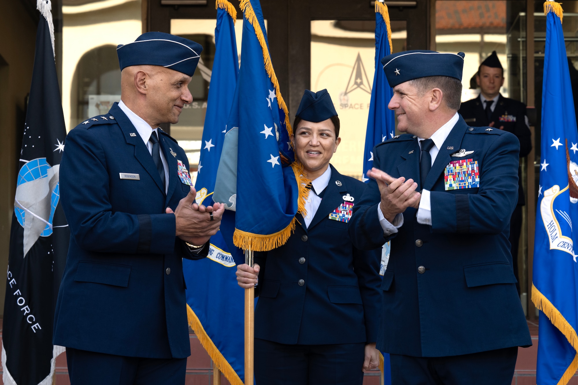 U.S. Air Force Lt. Gen. Brian Robinson (left), commander of Air Education and Training Command, and Brig. Gen. Christopher Amrhein, Air Force Accessions Center commander, clap after unveiling the center’s new guidon during an activation ceremony and assumption of command at Joint Base San Antonio-Randolph, Texas, Dec. 2, 2024.