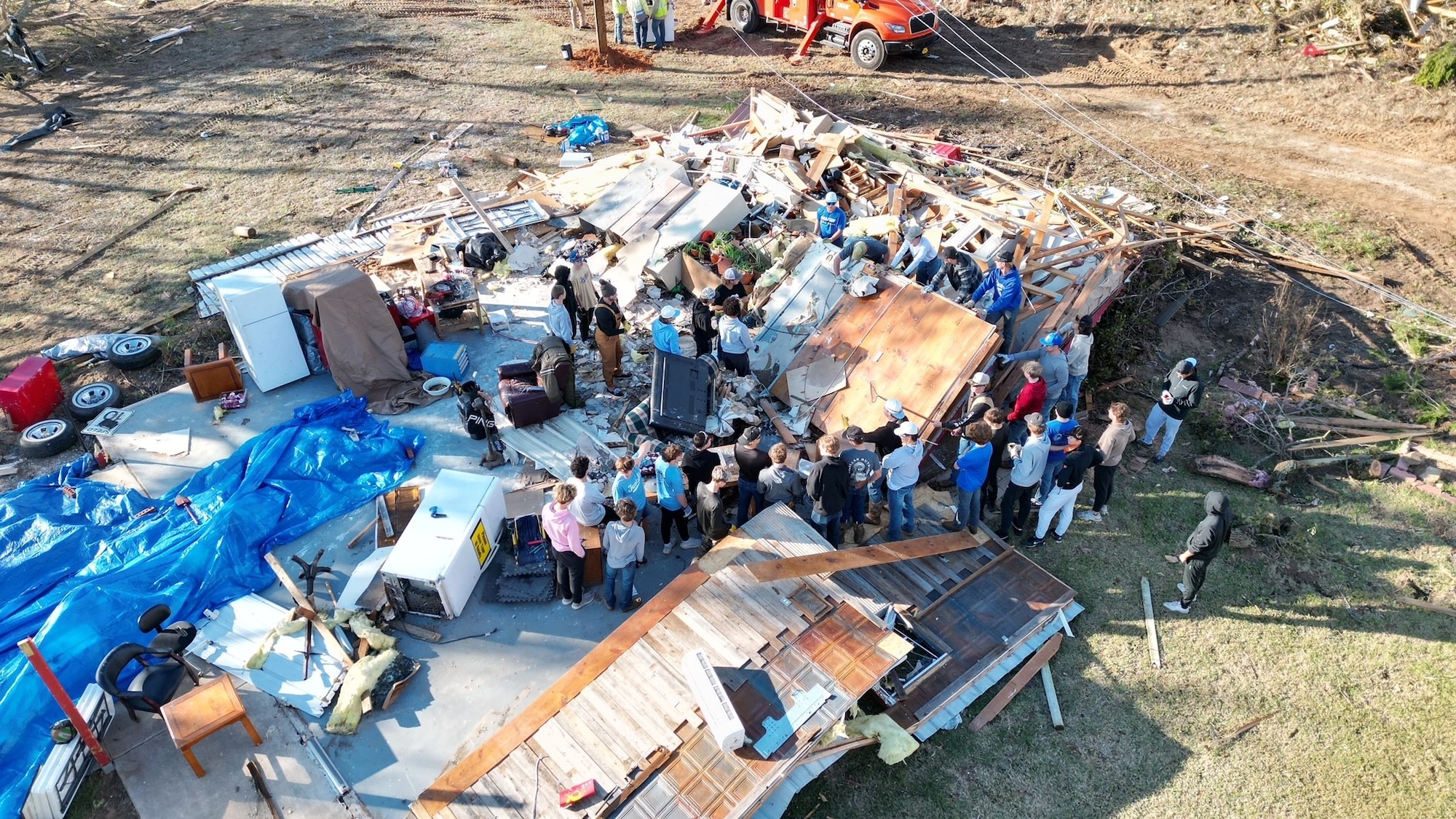 Group of people assisting and retrieving items from tornado damaged.