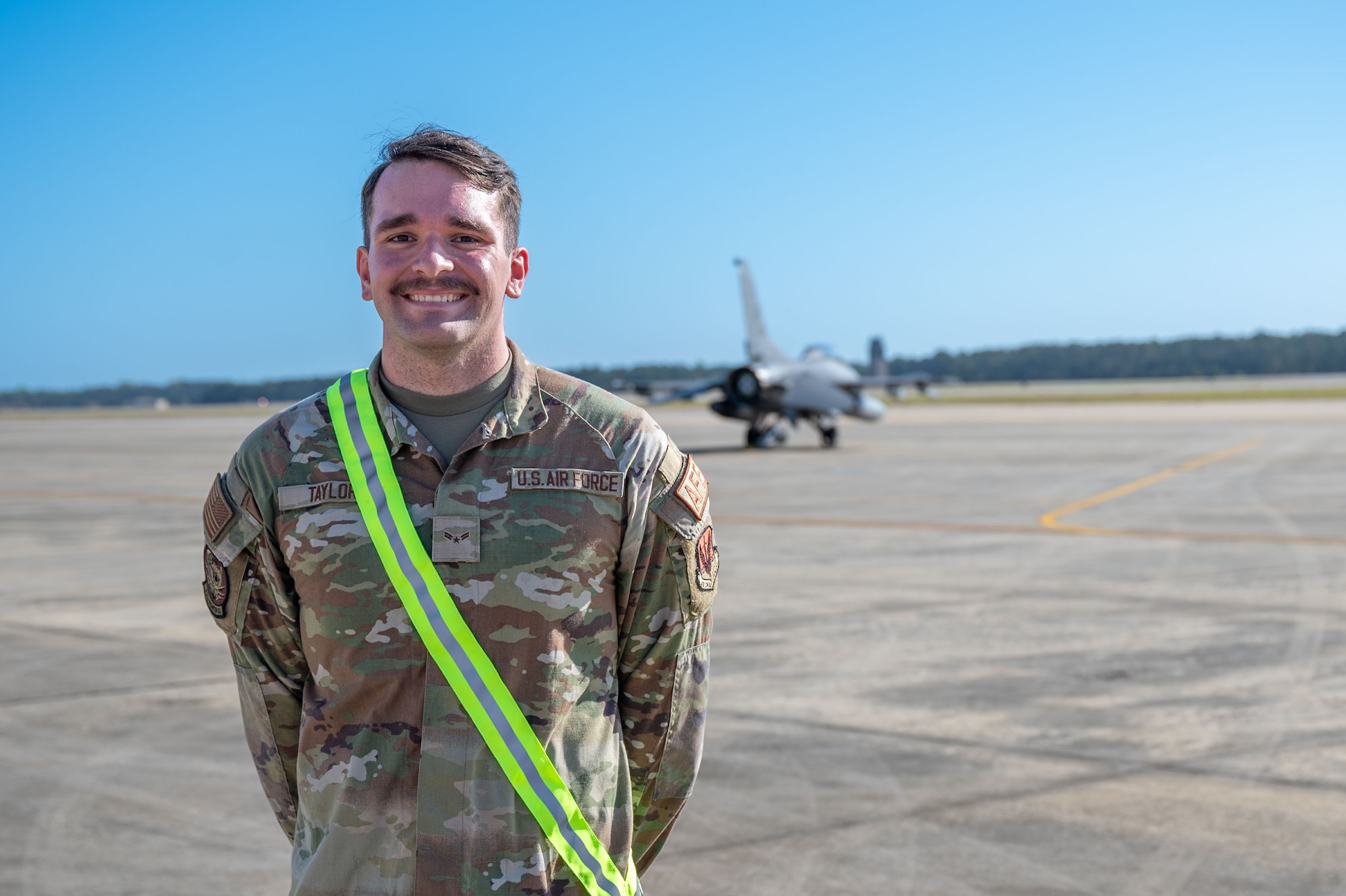An Airmen poses for a photo on the flightline.