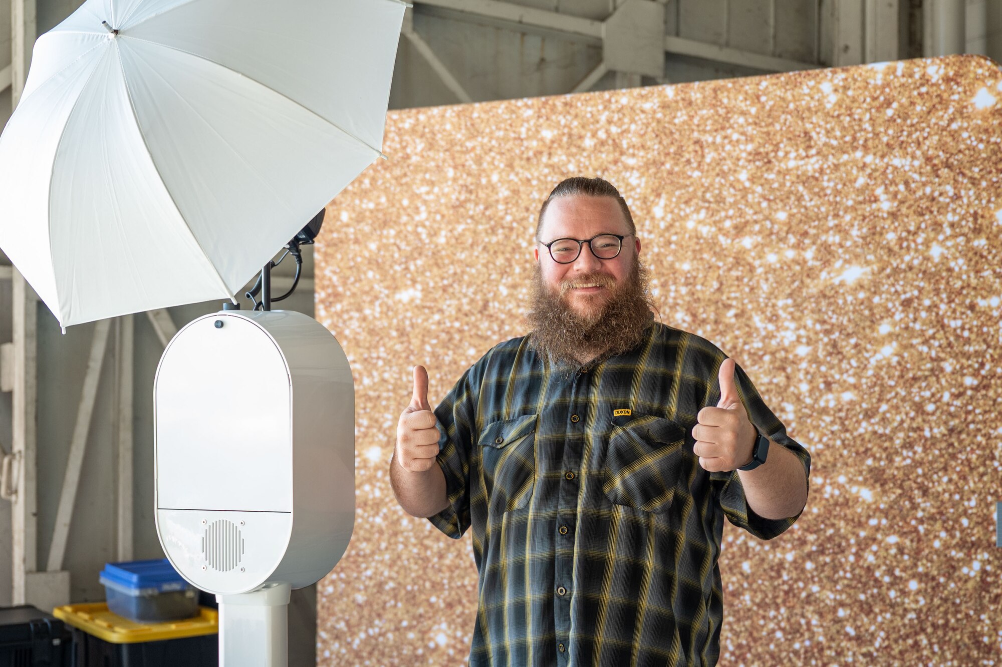A man poses for a photo by a camera and backdrop.