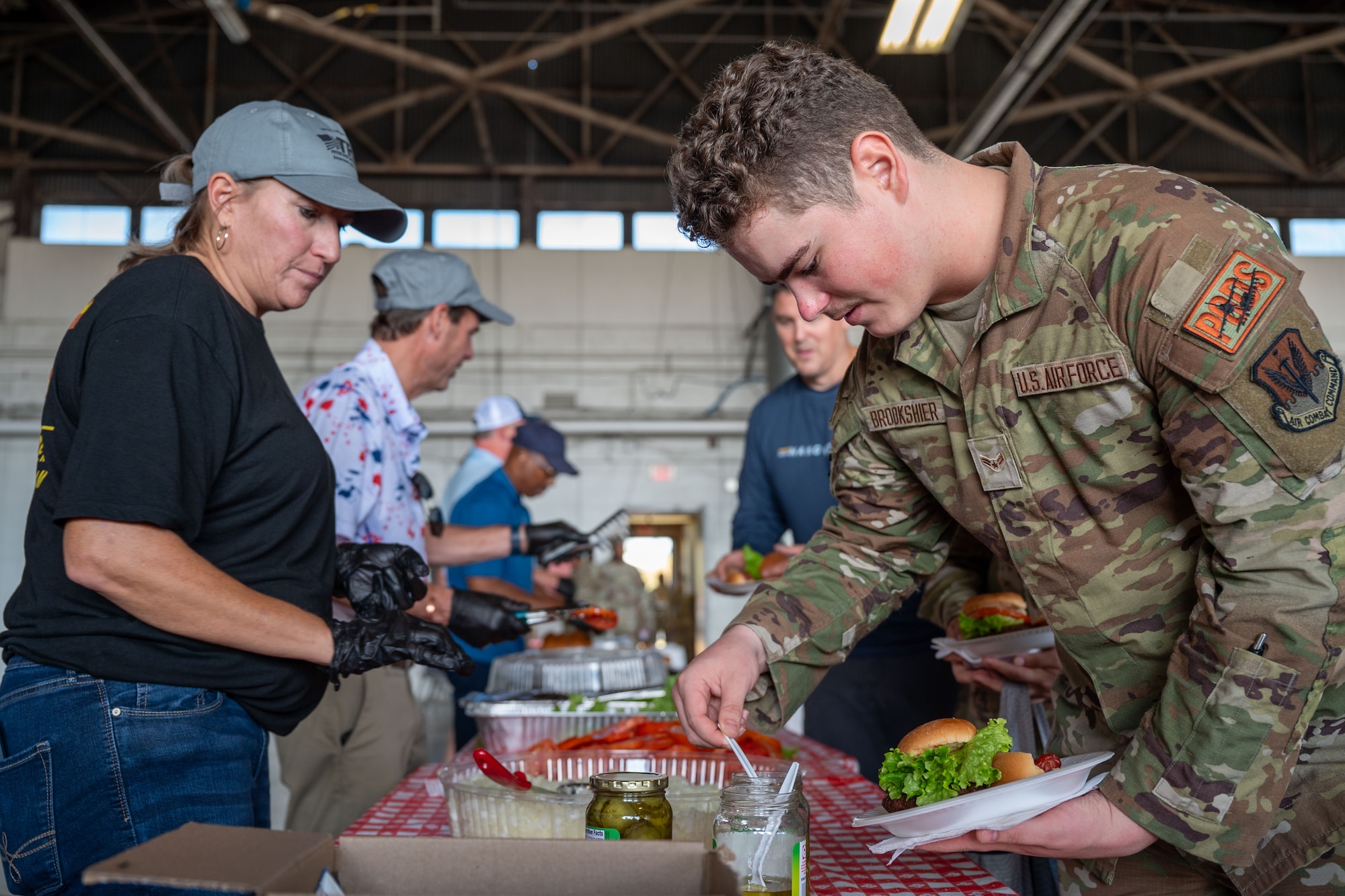 A service members adds food to his plate going down a buffet line.