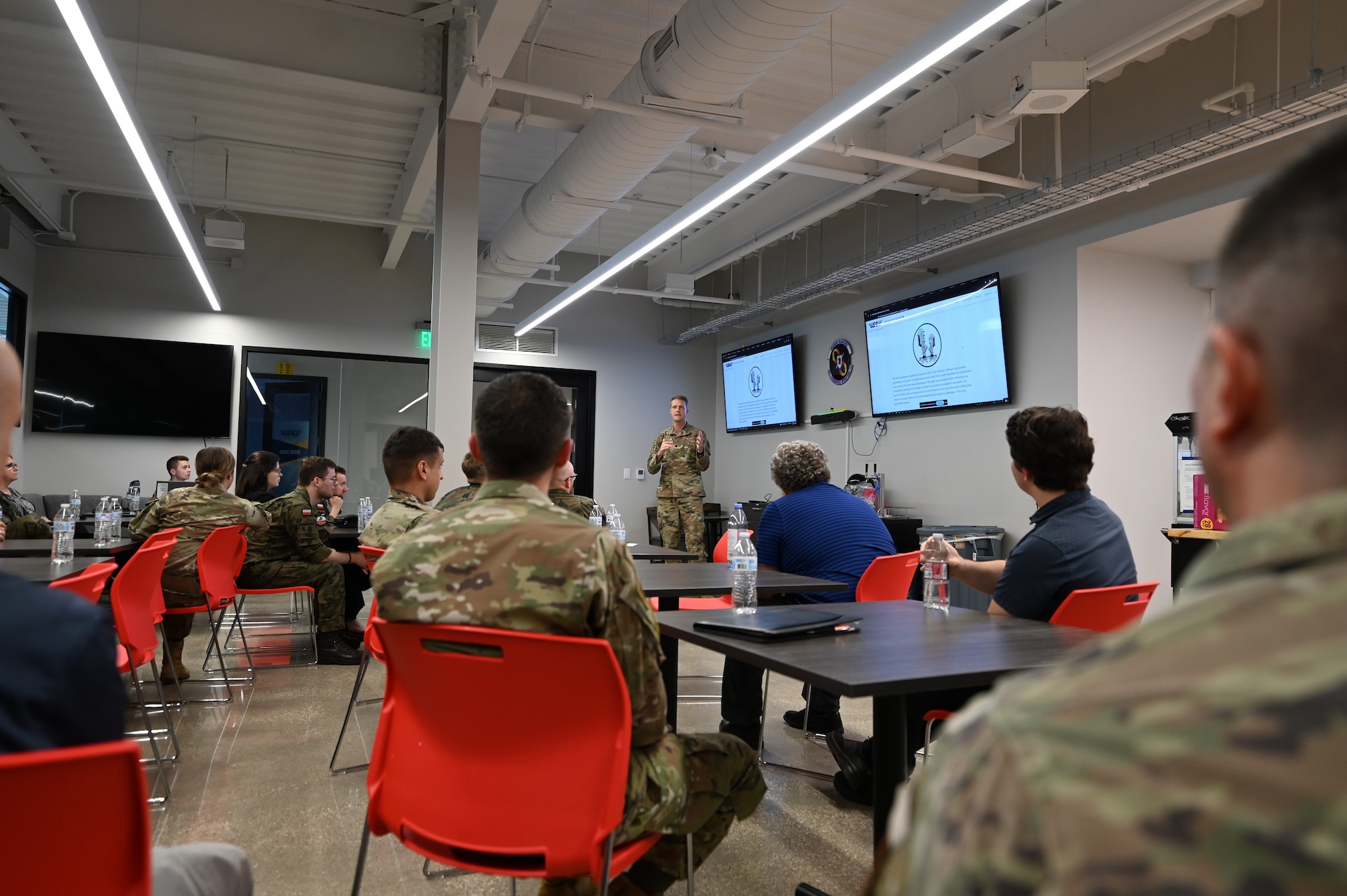 Polish and U.S. Air Force Airman stand in a breakroom and talk.