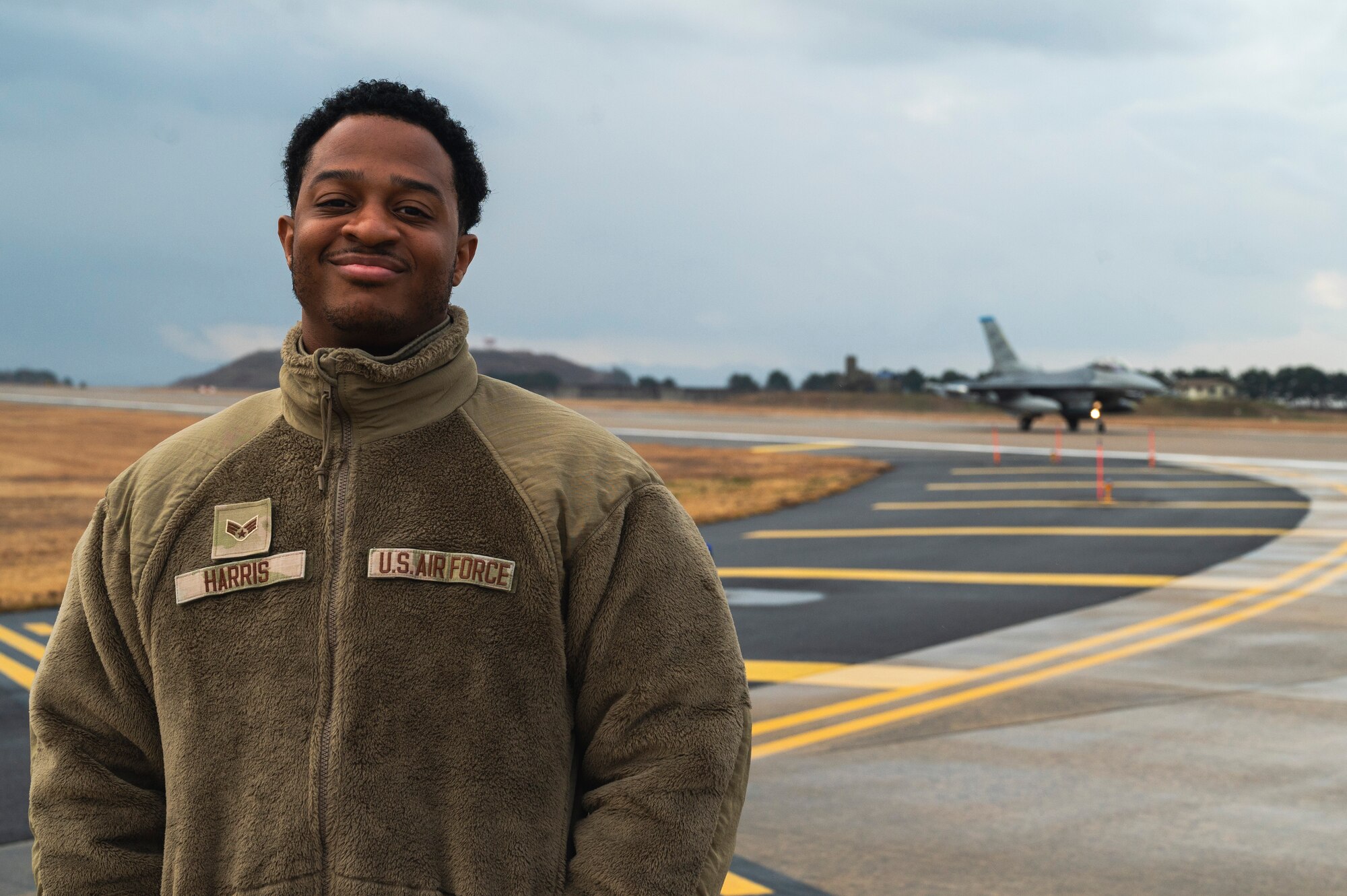 Senior Airman Nigel Harris, 8th Operational Support Squadron airfield management specialist, poses for a photo on the flightline.