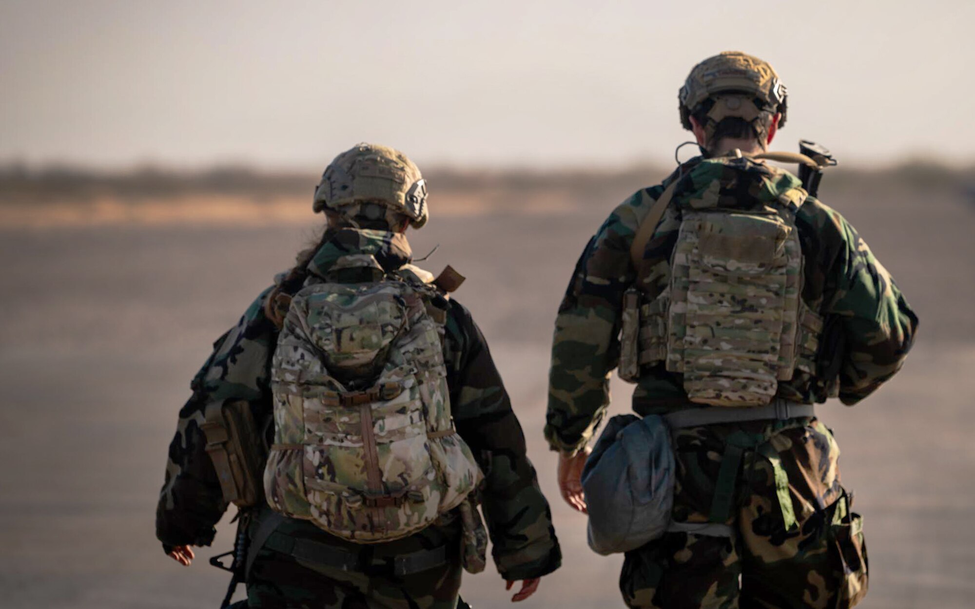 Two 944th Fighter Wing U.S. Air Force Reserve Citizen Airmen dawn their Mission Oriented Protective Posture (MOPP) gear and walk together after completing a patrol during Exercise Desert Hammer 25-1 at Auxiliary Field 6 near Gila Bend, Ariz., Nov. 15, 2024. This large-scale exercise showcases the adaptability of Mission Ready Airmen, advancing the skills needed to thrive in the rapidly evolving challenges of global competition. (U.S. Air Force photo by Senior Airman Jacob Dastas)