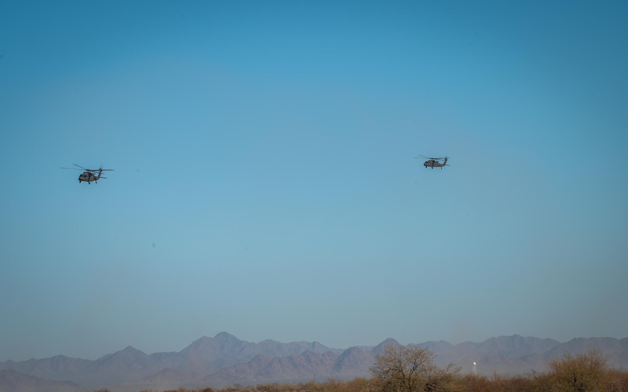 Two Arizona Army National Guard UH-60 Black Hawks fly over Auxiliary Airfield 6 near Gila Bend, Ariz., Nov. 14, 2024. Exercise Desert Hammer 25-1 emphasizes the U.S. Air Force Reserve’s commitment to readiness by integrating Agile Combat Support and Large Force Exercise capabilities in a contested environment. (U.S. Air Force photo by Senior Airman Jacob Dastas)