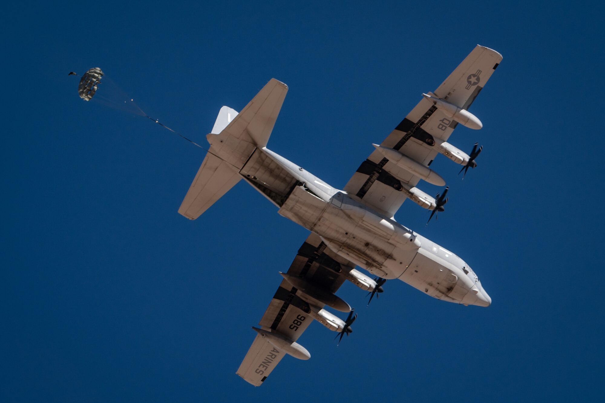 Cargo with a parachute begins to safely descend from a U.S. Marine Corps KC-130J Hercules during Exercise Desert Hammer 25-1 at Auxiliary Airfield 6 near Gila Bend, Ariz., Nov. 14, 2024. The exercise integrates Agile Combat Support and Large Force Exercise capabilities in a contested environment. (U.S. Air Force photo by Tech. Sgt. Tyler J. Bolken)