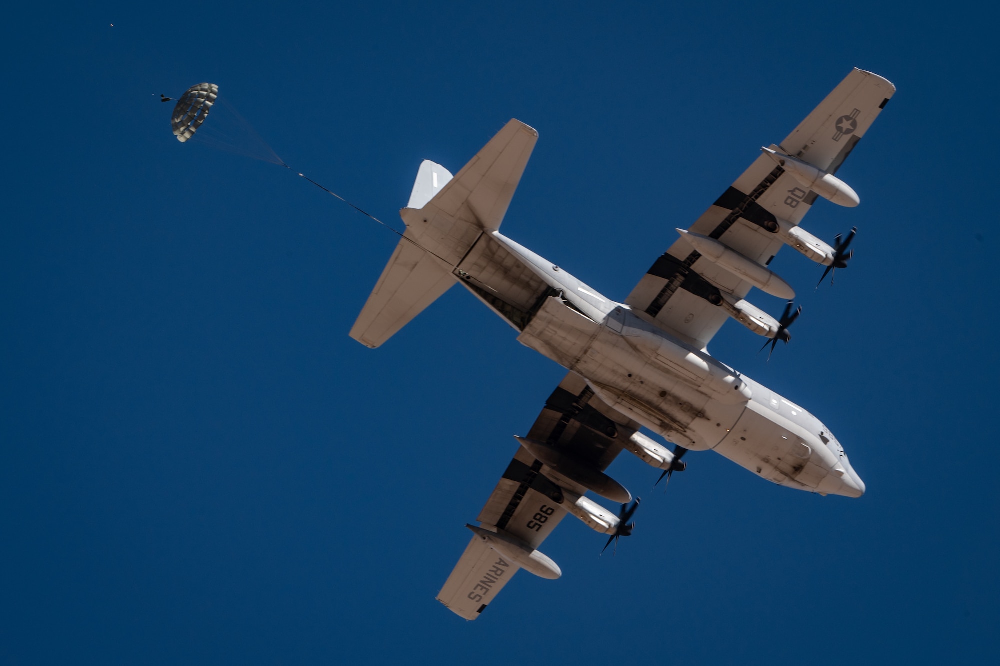 Cargo with a parachute begins to safely descend from a U.S. Marine Corps KC-130J Hercules during Exercise Desert Hammer 25-1 at Auxiliary Airfield 6 near Gila Bend, Ariz., Nov. 14, 2024. The exercise integrates Agile Combat Support and Large Force Exercise capabilities in a contested environment. (U.S. Air Force photo by Tech. Sgt. Tyler J. Bolken)