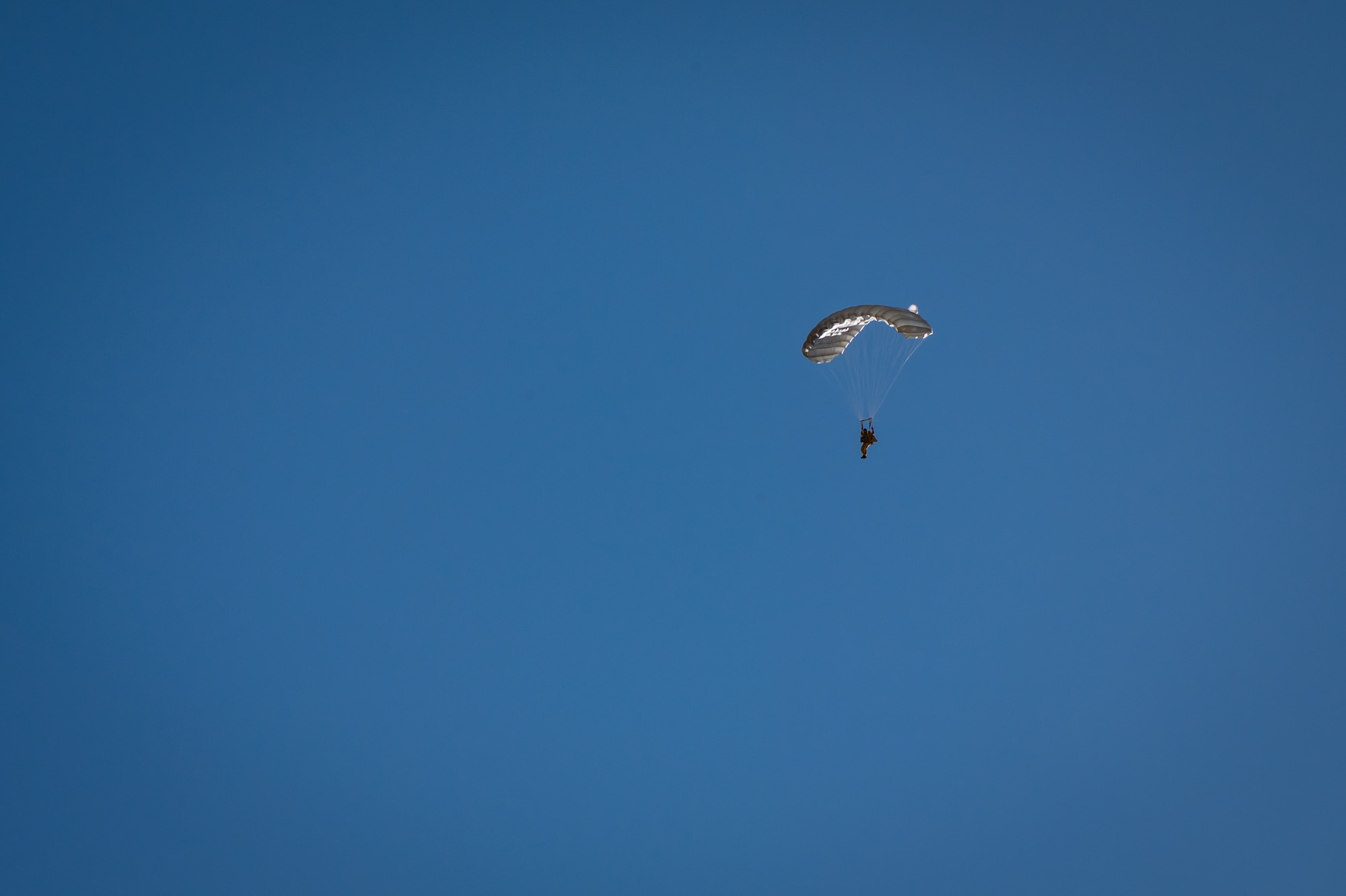 A U.S. Air Force Airman descends under canopy during a personnel airdrop at Exercise Desert Hammer 25-1, held at Auxiliary Airfield 6 near Gila Bend, Ariz., Nov. 14, 2024. Through joint and multinational collaboration, Desert Hammer tests the ability of over 700 participants and 131 aircraft to operate, defend, and sustain airbases under austere conditions. (U.S. Air Force photo by Tech. Sgt. Tyler J. Bolken)