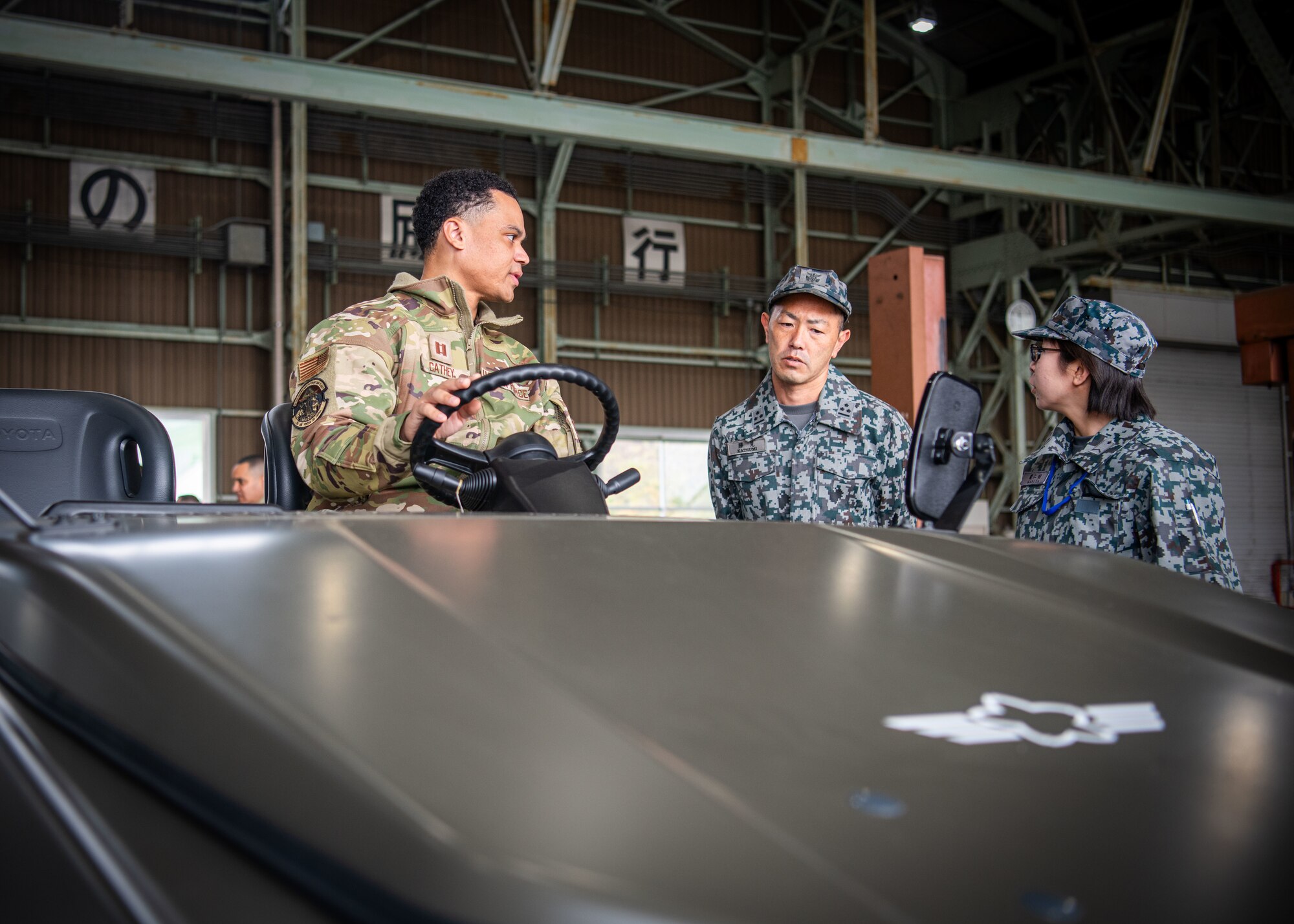 Airman engages with Japan Air Self-Defense Force vehicle maintenance personnel.