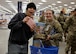 Two women, one in Army uniform and the other in black hat and sweat shirt, hold a clutch purse with smiling expressions after she had just won the purse from the Post Exchange.