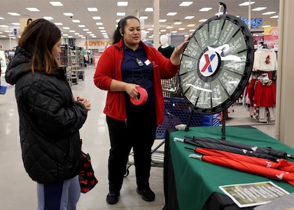 A woman spins a prize wheel while another woman watches at the Post Exchange