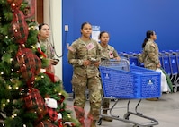 Three female Soldiers enter the Post Exchange by a Christmas Tree and pushing a shopping cart.