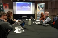 Members from artic region sit at a table with coffee and printed slides at a networking and outreach event.