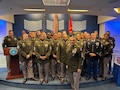 Top 32 Recruiters for Fiscal Year 24 pose in the Hall of Heroes for a group photo, all wearing the ASGU