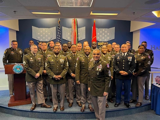 Top 32 Recruiters for Fiscal Year 24 pose in the Hall of Heroes for a group photo, all wearing the ASGU