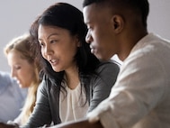 An asian woman and a black man looking at the same computer screen and discussing their work