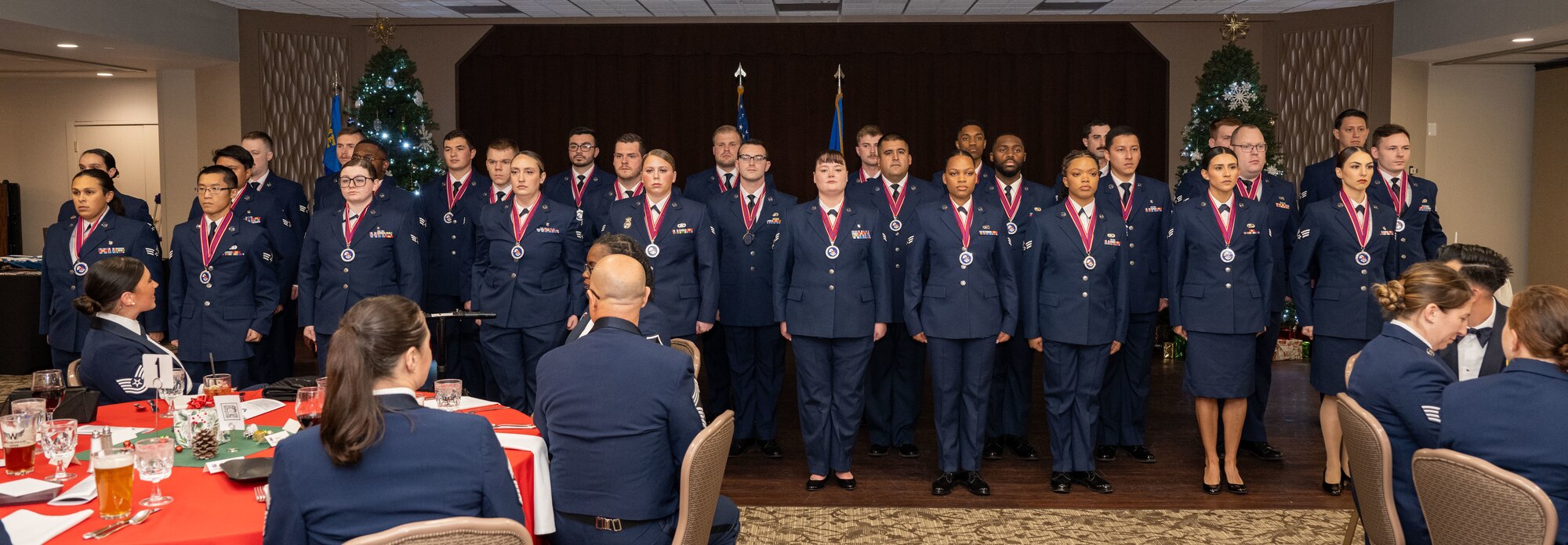 Military members pose for a group photo at the end of a graduation ceremony.