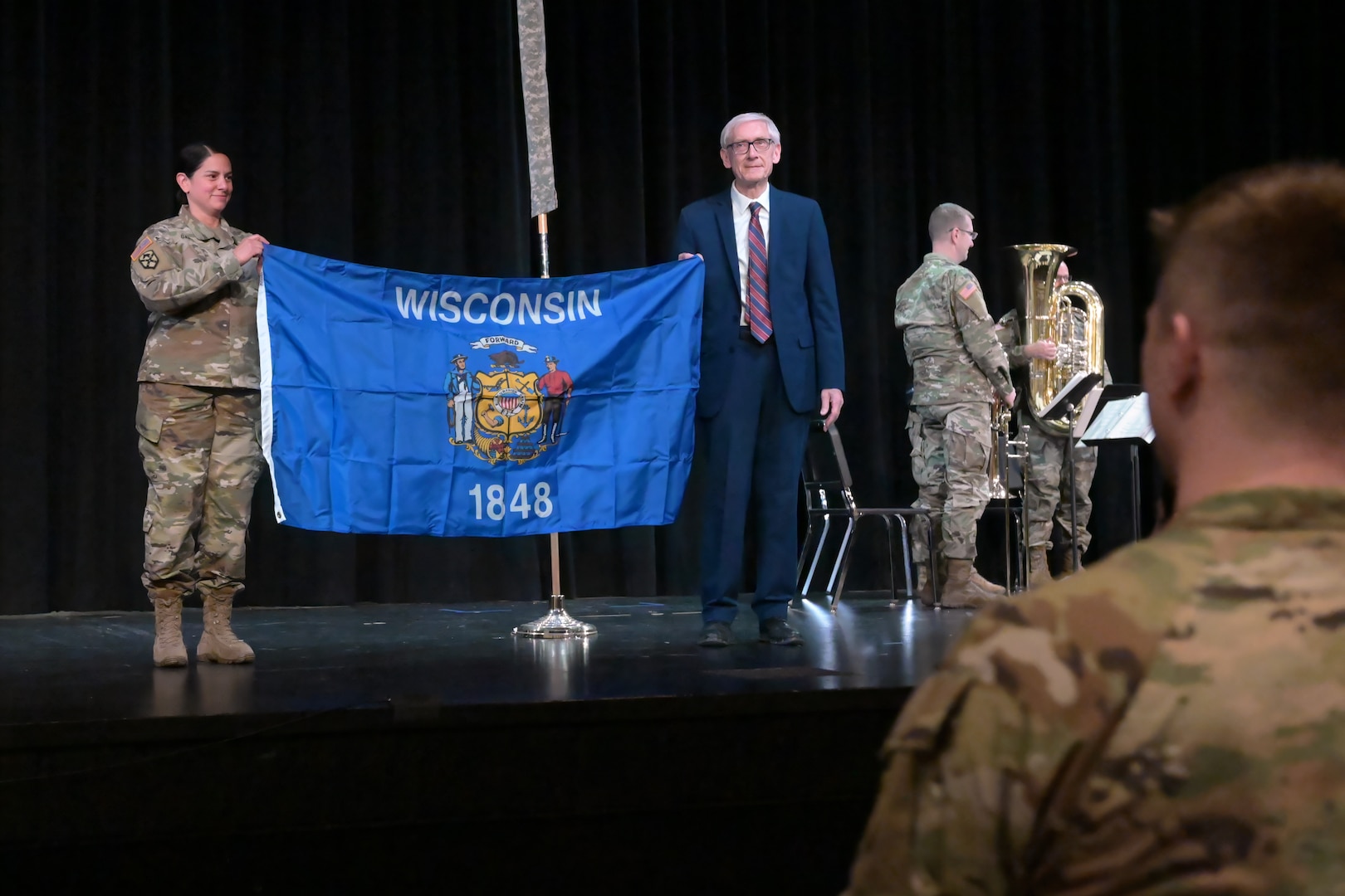 U.S. Army Lt. Col. Maria Garcia, commander of the Wisconsin Army National Guard’s 732nd Combat Sustainment Support Battalion, accepts a Wisconsin state flag from Wisconsin Governor Tony Evers Nov. 30, 2024, during a deployment sendoff ceremony at Tomah High School in Tomah, Wisconsin.