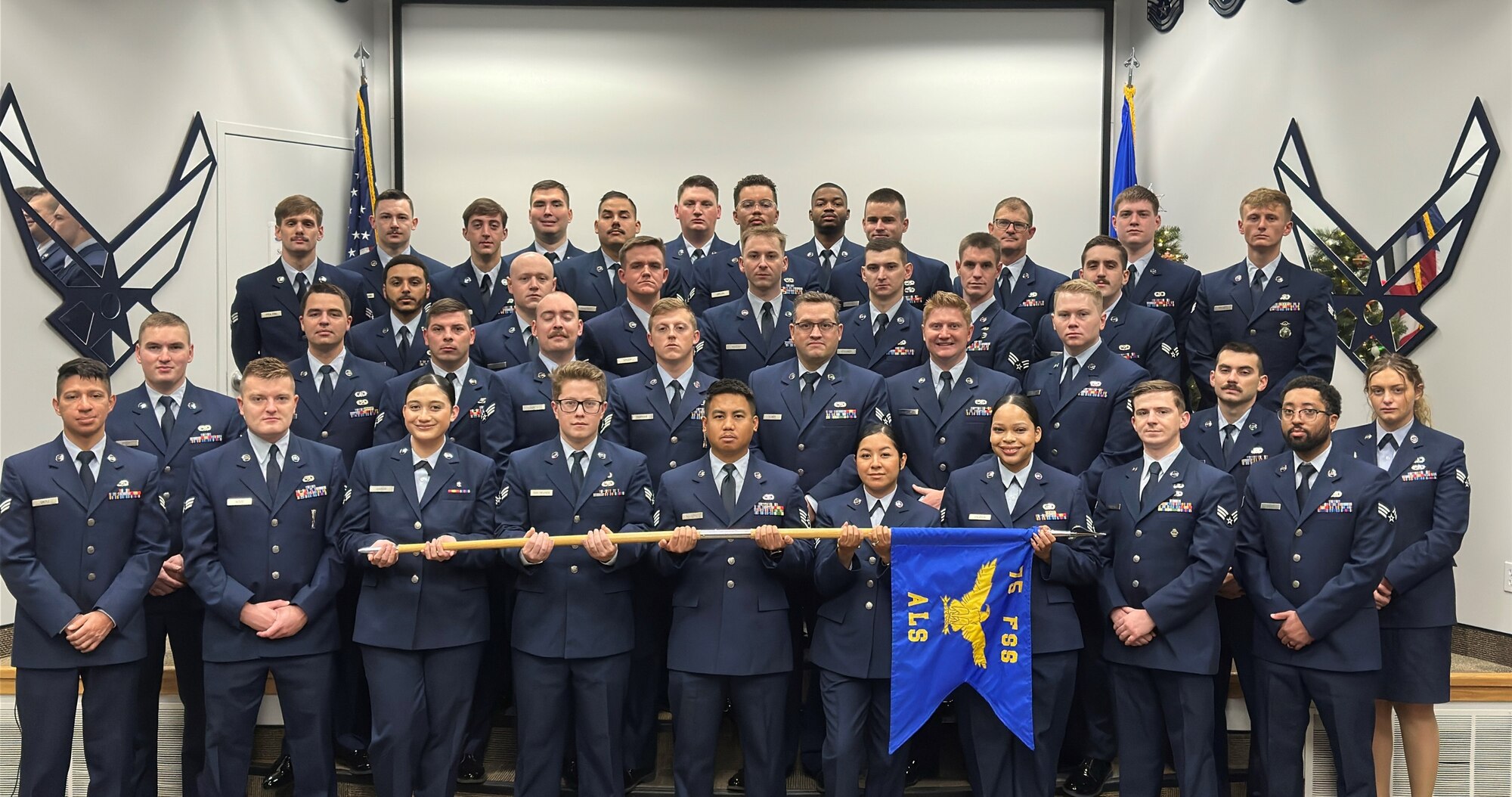 A group of Airmen in dress blues stand in formation.