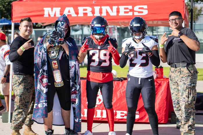 U.S. Marine Corps Staff Sgt. William Cary, far left, a recruiter with Recruiting Sub Station Pearland, Recruiting Station Houston, and Sgt. Jesusaleja Arredondo, far right, a recruiter with RSS Baybrook, RS Houston, pose for a photo with football fans during the Houston Texans vs. Tennessee Titans football game at NRG Stadium in Houston, Texas, Nov. 24, 2024. Marines with RS Houston challenged fans with a pull-up challenge to win prizes to support the National Football League's Salute To Service game along with the other military branches. (U.S. Marine Corps photo by Sgt. Ryan H. Pulliam)