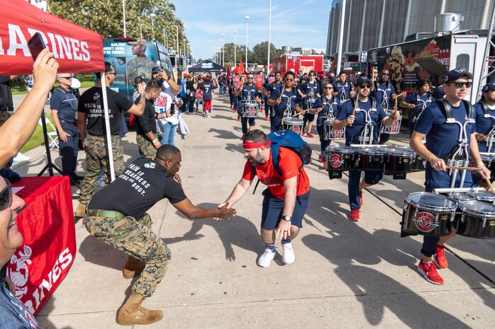 U.S. Marine Corps Staff Sgt. Adrien Hogan, Jr., foreground, with Recruiting Sub Station Humble, Recruiting Station Houston, high-fives a fan at a parade during the Houston Texans vs. Tennessee Titans football game at NRG Stadium in Houston, Texas, Nov. 24, 2024. Marines with RS Houston challenged fans with a pull-up challenge to win prizes to support the National Football League's Salute To Service game along with the other military branches. (U.S. Marine Corps photo by Sgt. Ryan H. Pulliam)