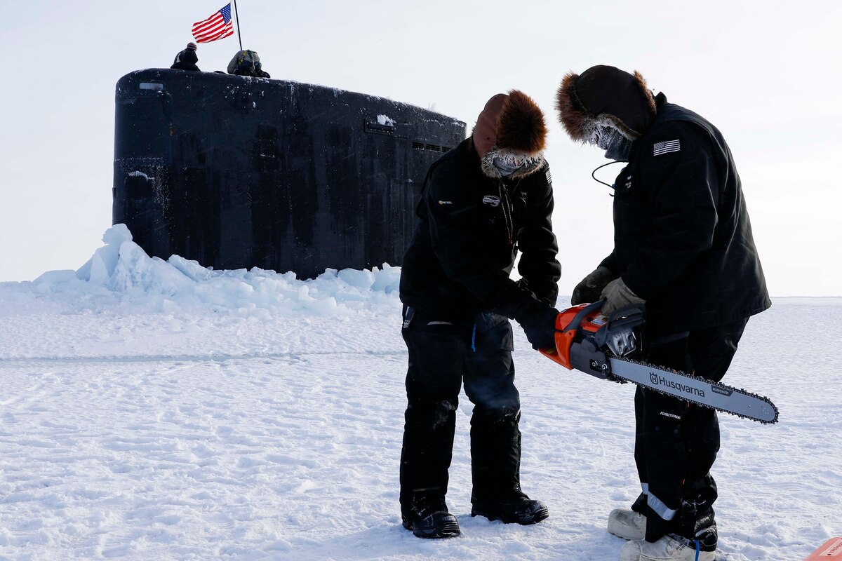 Technicians start a power saw to clear ice from a submarine breaching through ice in the Arctic.
