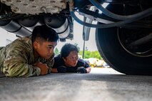 U.S. Air Force Staff Sgt. Gabriel Pereda, 35th Logistics Readiness Squadron (LRS) Ground Transportation operator, and a LRS Ground Transportation member crawl under a wrecker to inspect its parts at Misawa Air Base, Japan, Aug. 28, 2024.