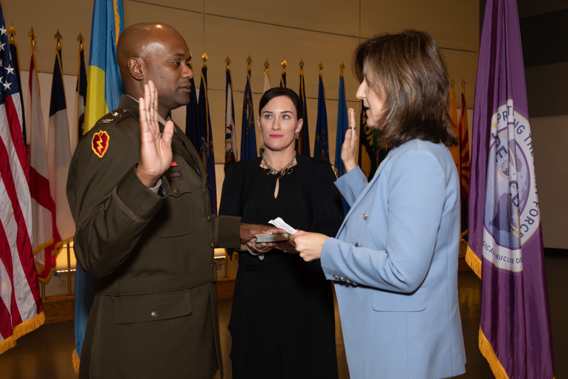 COL Owen Roberts II reaffirms his Oath of Office, administered by Ms. Nicole Kilgore, Deputy Joint Program Executive Officer for Chemical, Biological, Radiological and Nuclear Defense, with support from his wife, Erin Roberts.