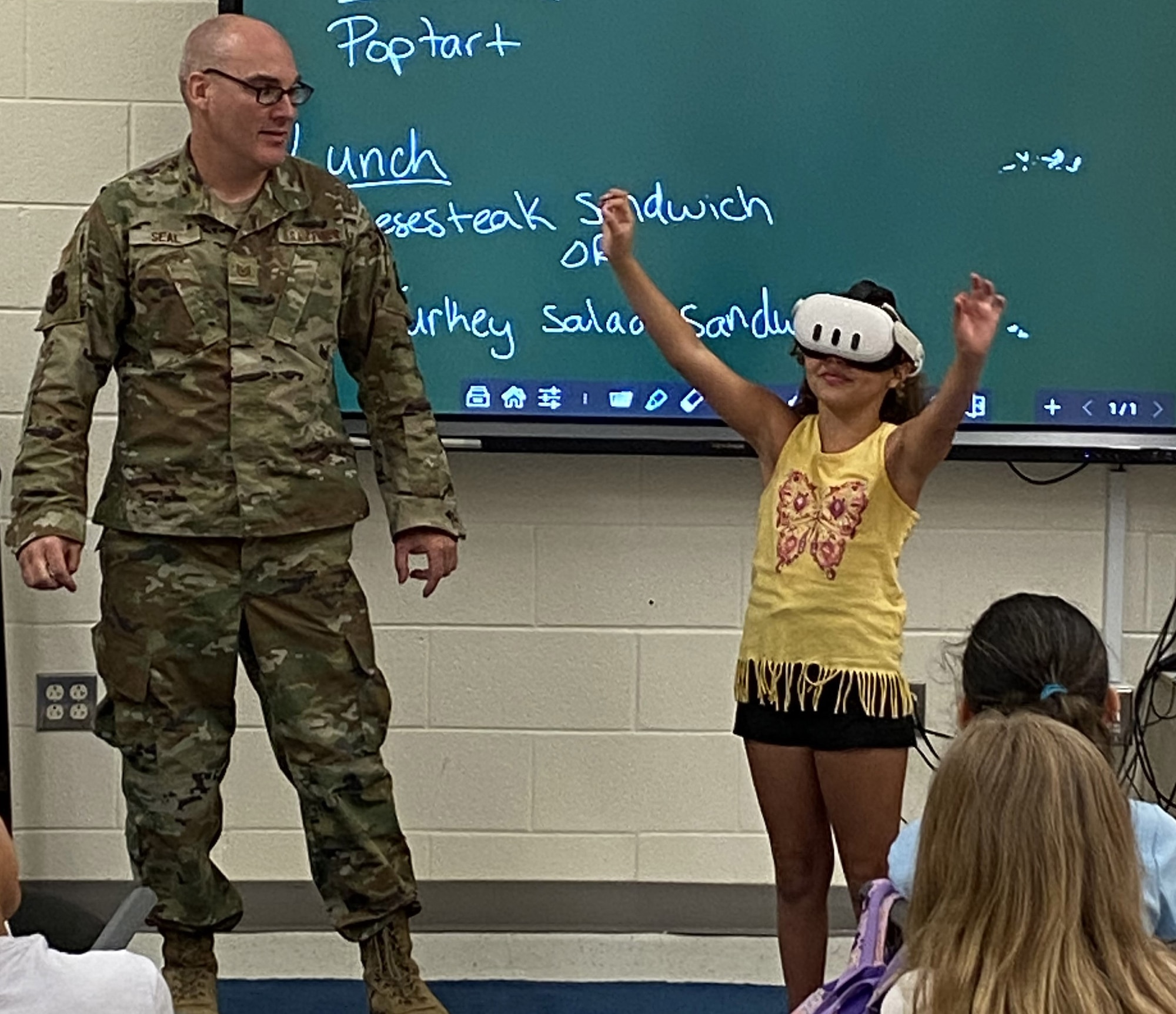 U.S. Air Force Tech. Sgt. Scott Seal, 305th Maintenance Group KC-46 VR training lead and hydraulics instructor, provides a STEM student an opportunity to watch one of his VR creations on a headset at Denbo-Crichton School, Browns Mills, N.J., July 16, 2024. Seal, stationed at Joint Base McGuire-Dix-Lakehurst, N.J, volunteers his time at local science, technology, engineering and math summer programs and camps providing students demonstrations and hands-on involvement in immersive technology. (Courtesy photo)