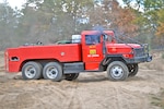 Men drive a firefighting truck around an off-road vehicle testing area.