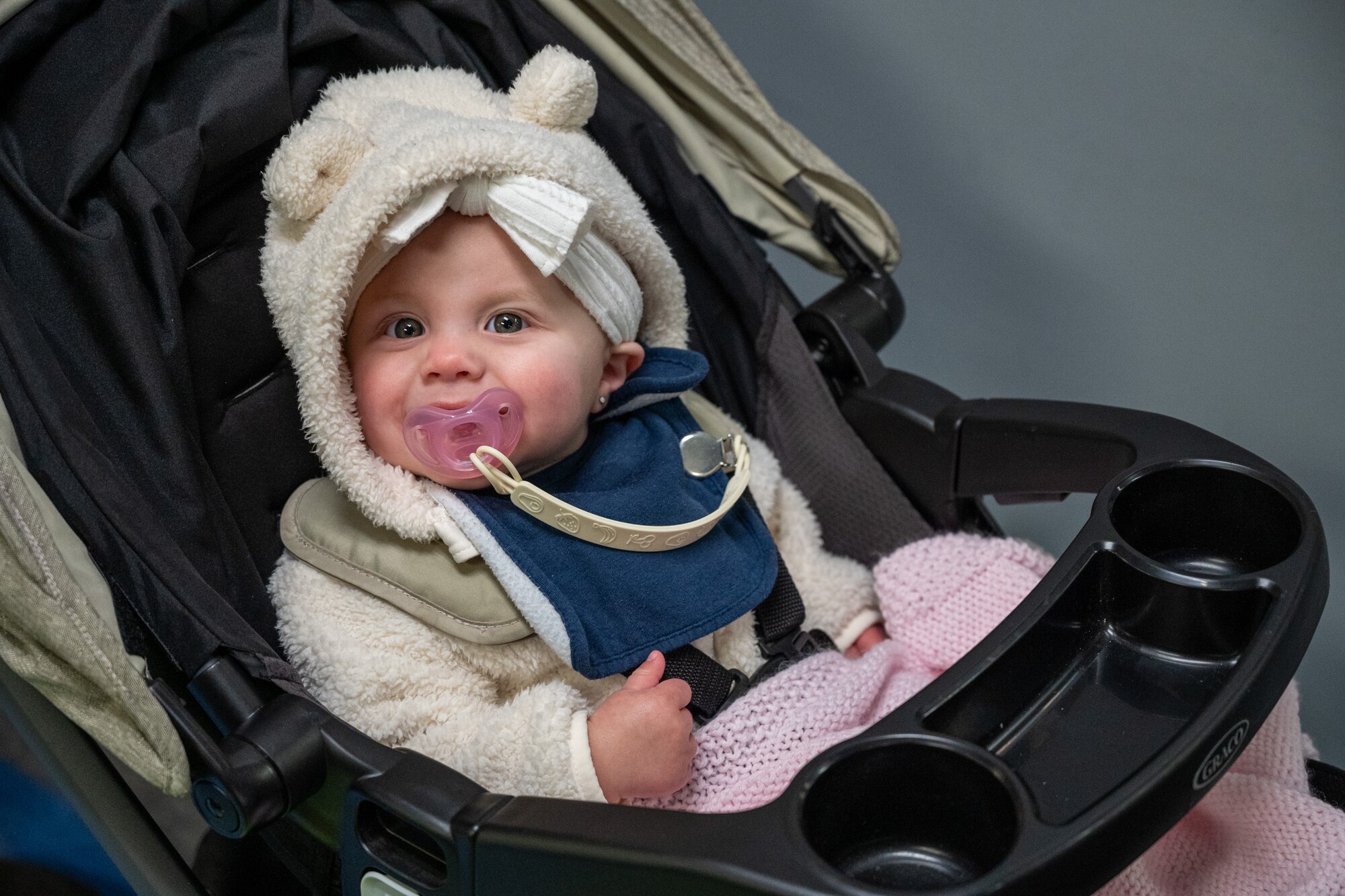 A baby smiles inside the Sounder facility after the annual Team McChord holiday tree lighting ceremony at Joint Base Lewis-McChord, Washington, Dec. 5, 2024.