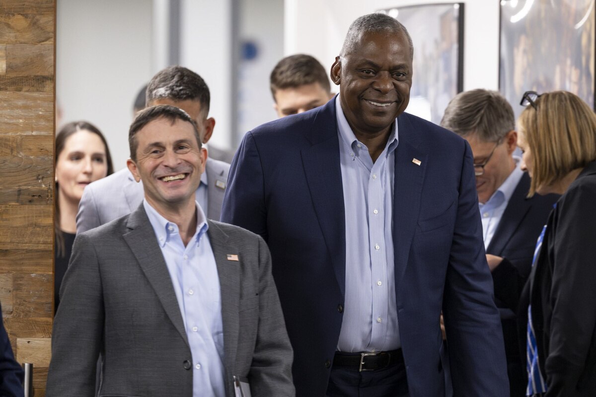 Two men smiling in business suits walk inside a building.