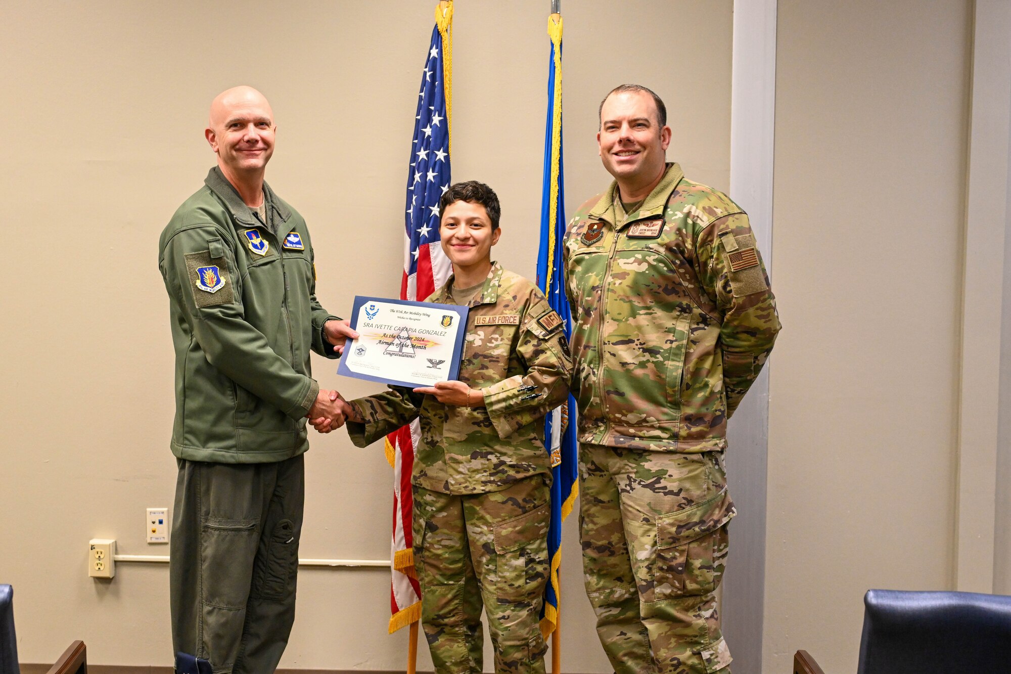 U.S. Air Force Col. Jeff Marshall, 97th Air Mobility Wing commander, presents the October Airman of the Month certificate to Senior Airman Carapia Gonzalez, 97th Operational Medical Readiness Squadron aerospace medical technician, alongside Chief Master Sgt. Justin Brundage, 97th Air Mobility Wing command chief, at Altus Air Force Base, Oklahoma, Dec. 2, 2024. Aerospace medical technicians care for permanent party, student flyers, and civilian personnel with flight, medical, and occupational exams, flyer sick call, and squadron welfare visits. (U.S. Air Force photo by Senior Airman Miyah Gray)