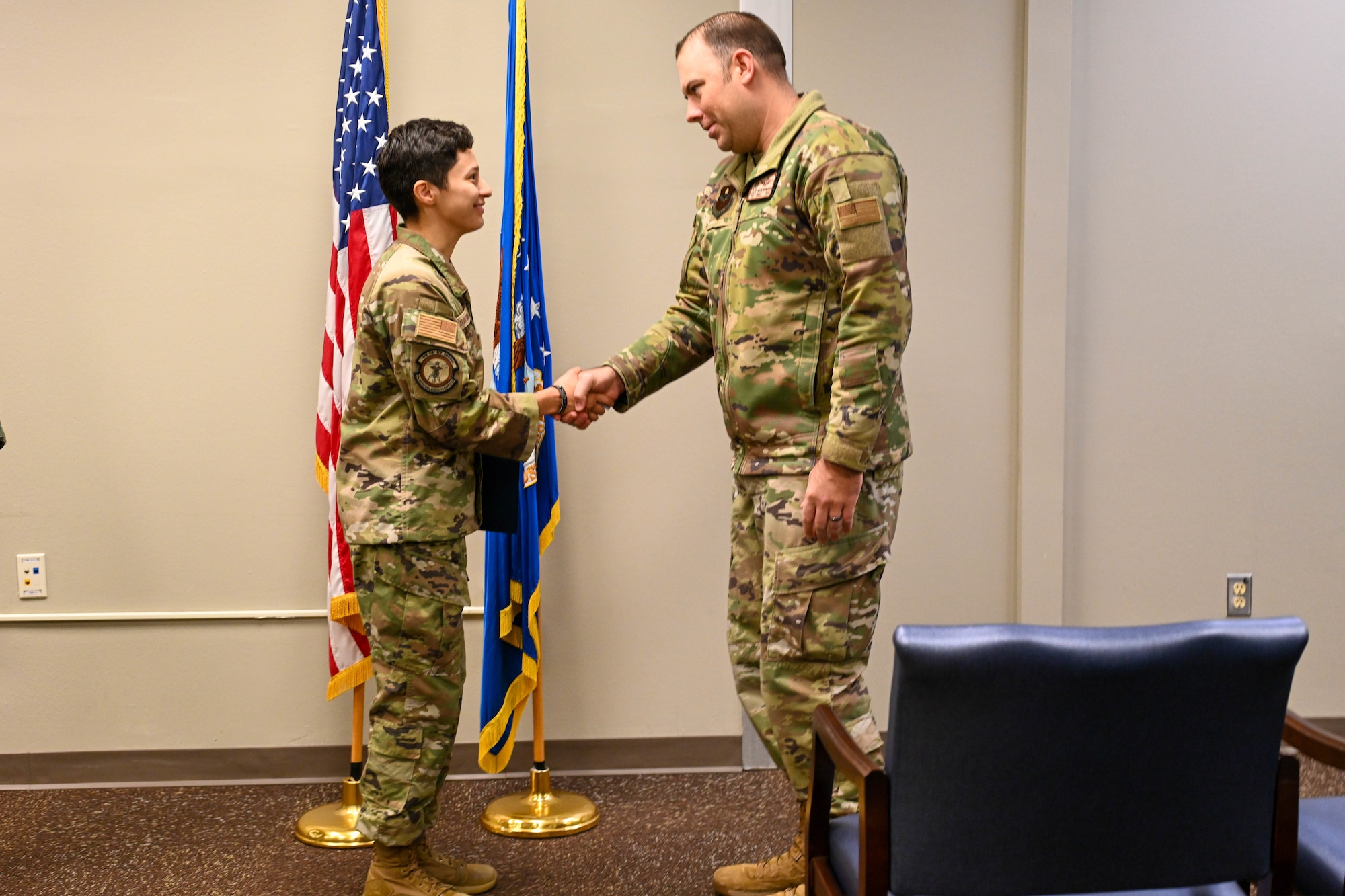 U.S. Air Force Senior Airman Carapia Gonzalez, 97th Operational Medical Readiness Squadron aerospace medical technician, shakes hands with Chief Master Sgt. Justin Brundage, 97th Air Mobility Wing command chief, at Altus Air Force Base, Oklahoma, Dec. 2, 2024. Gonzalez joined the Air Force with the intention to help as many people as she could. (U.S. Air Force photo by Senior Airman Miyah Gray)