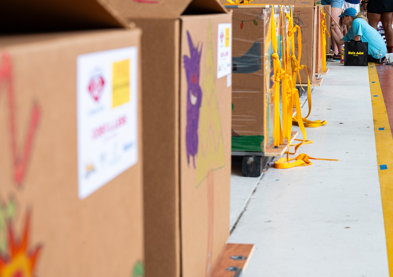 A small group of people decorate at the end of a long row of boxes.