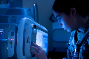 Airman uses an x-ray machine in blue lighting.