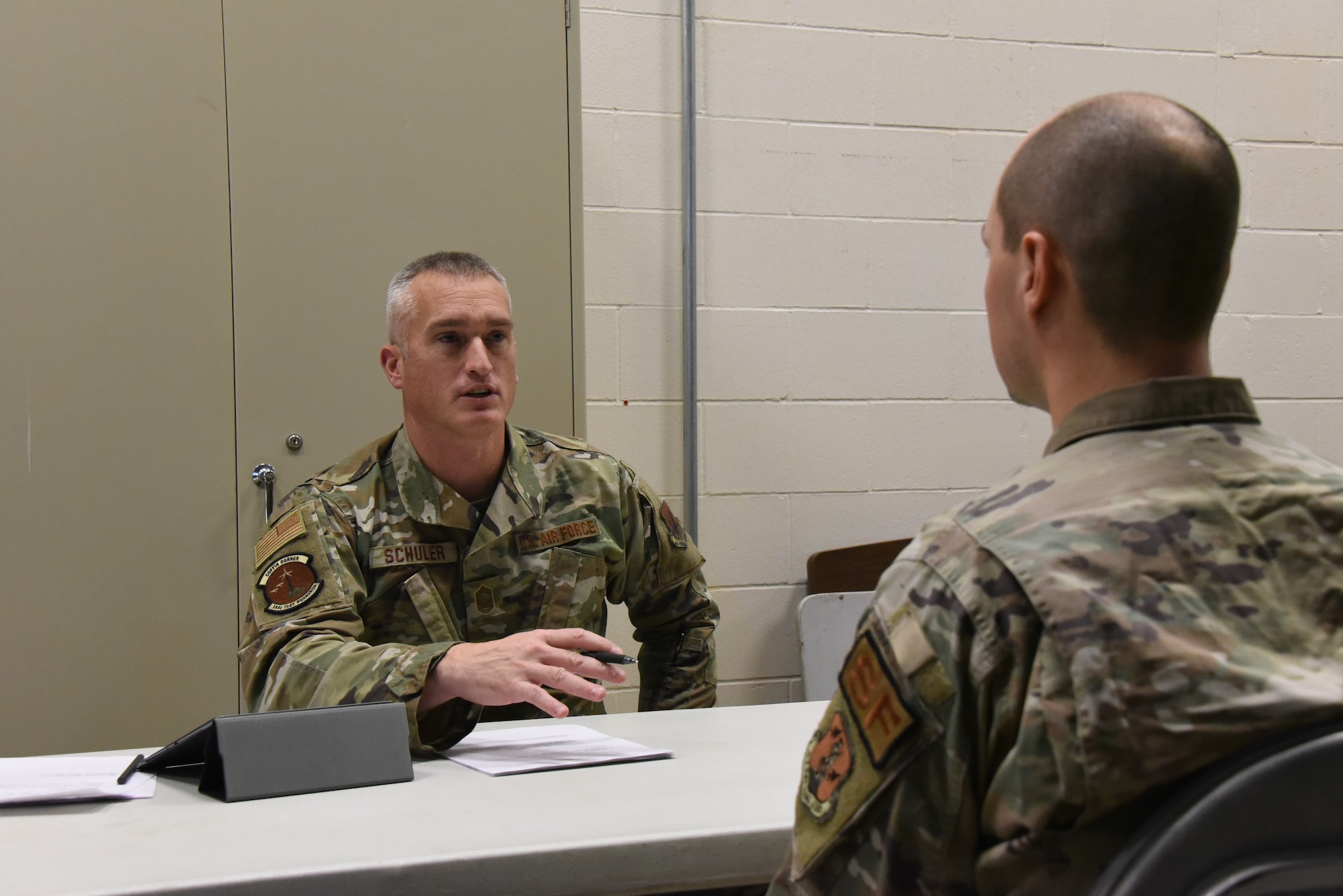 Chief Master Sgt. Scott Schuller sits and speaks at a table to Staff Sgt. Ethan Druin