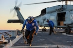Seaman Gen Repatacodo removes the chains from a MH-60R from Helicopter Maritime Squadron 79 during flight operations aboard the guided-missile destroyer USS Arleigh Burke (DDG 51), Oct. 21, 2024