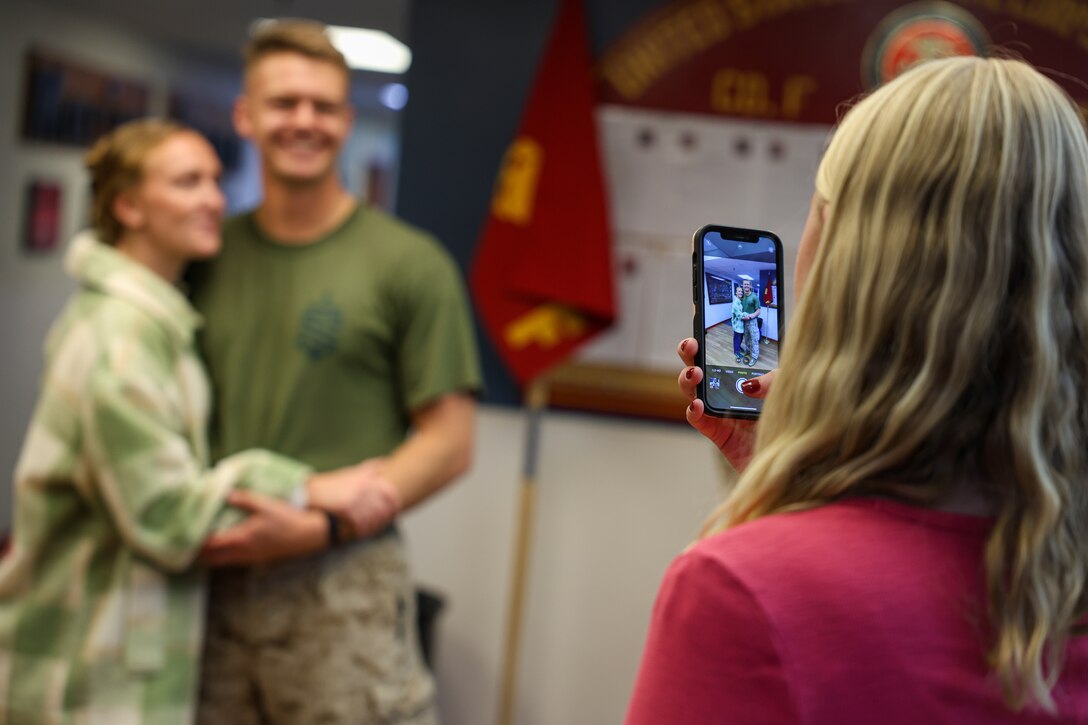 U.S. Marine Corps Cpl. Jackson Wayne Paul, infantry rifleman with Fox Company, 2nd Battalion 23d Marine Regiment, 4th Marine Division, poses for a picture with his wife while his sister takes a photo of them before saying their goodbyes for the unit deployment program at Camp Williams, Utah, Nov. 3, 2024. The activation marks the beginning of an intensive period of training for 2nd Battalion, 23d Marines as they provide a total force solution in support of the UDP by aligning Marine Forces Reserve’s commitment to Marine Corps strategic objectives. This marks the first time since 2020 that an entire Reserve infantry battalion has activated to support the Unit Deployment Program. (U.S. Marine Corps photo by Cpl. Aaron TorresLemus)