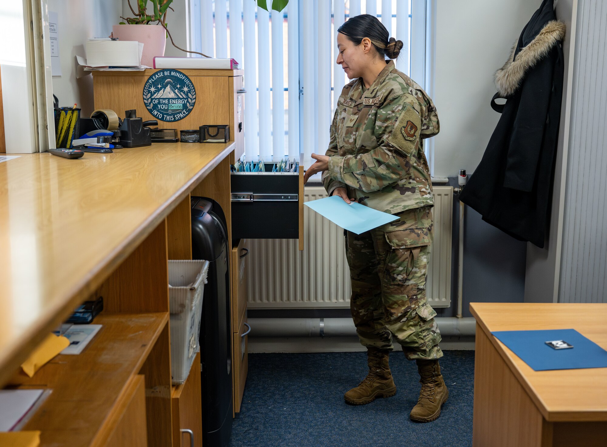 U.S. Air Force Staff Sgt. Selena Ramirez, 100th Force Support Squadron noncommissioned officer in charge of official passports, assists a customer picking up their passport at Royal Air Force Mildenhall, England, Dec. 6, 2024.