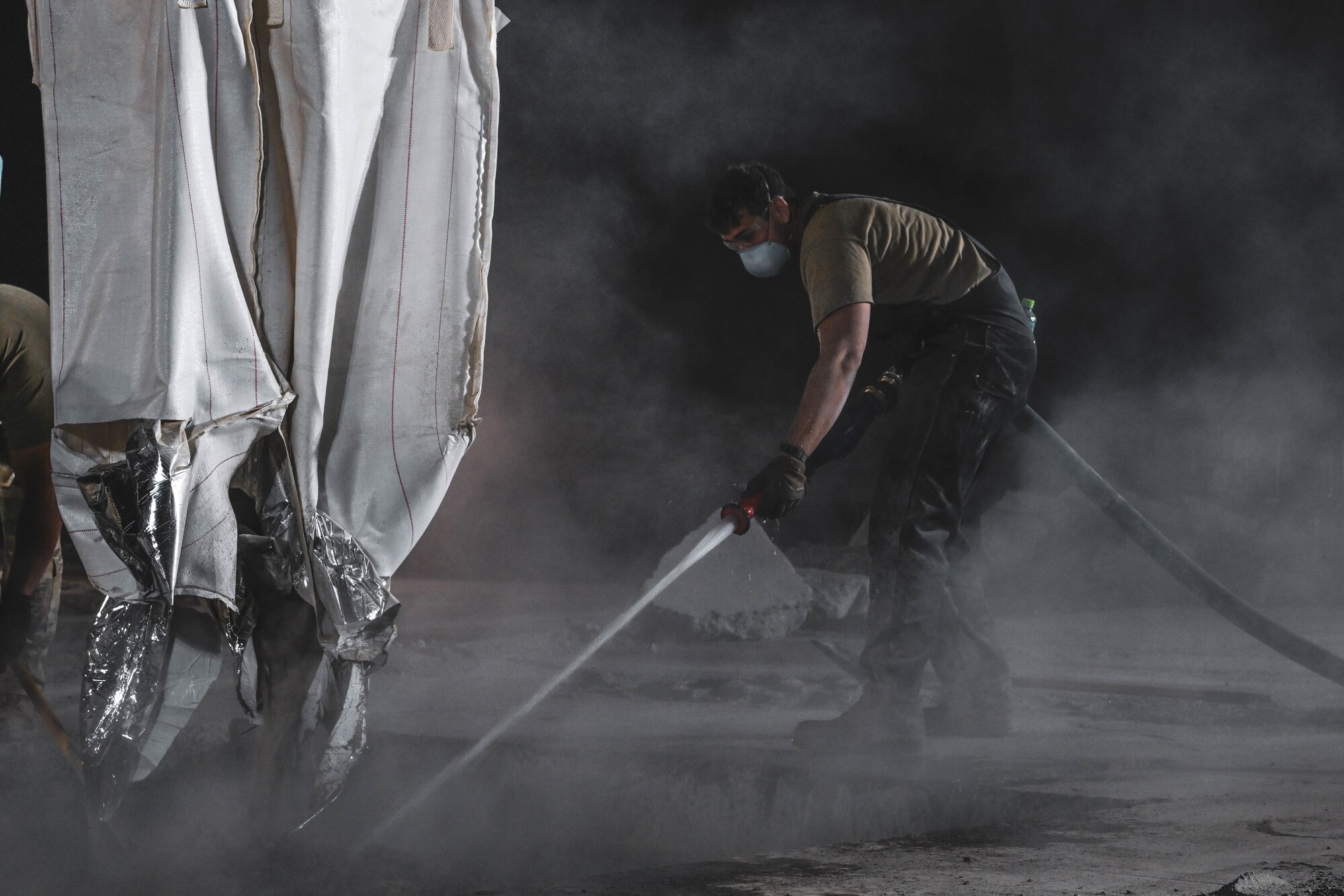 An Airman sprays water onto concrete during an exercise.