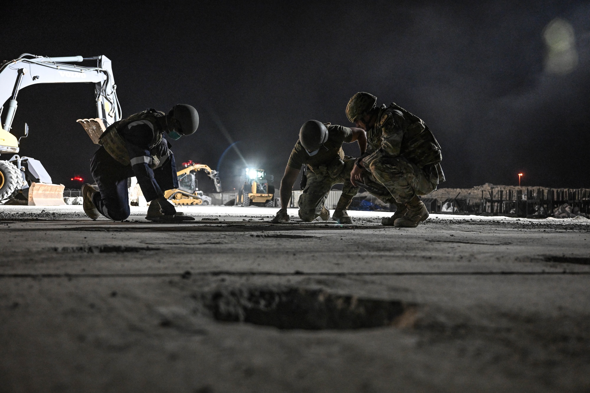 Three Airmen smooth out concrete during an exercise.