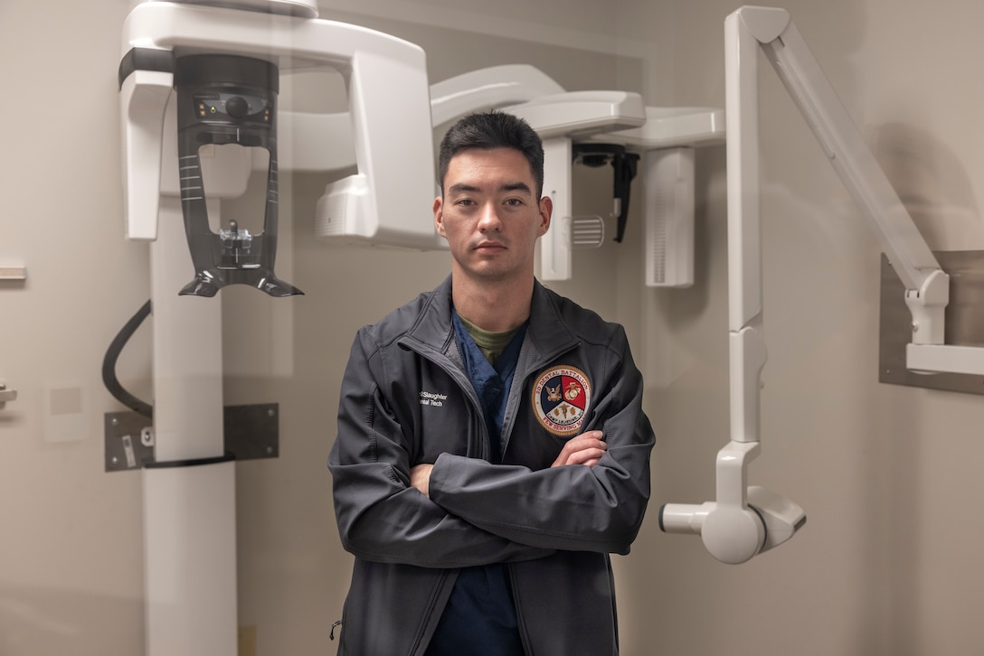 U.S. Navy Hospital Corpsman 3rd Class Cody Slaughter, a dental assistant with 2nd Dental Battalion, 2nd Marine Logistics Group, and a native of Abilene, Texas, poses for a photo between dental x-ray machines on Camp Lejeune, North Carolina, Dec. 5, 2024. Slaughter was selected as warrior of the week for his dedication, leadership and work ethic that his command says sets him apart from his peers, ensuring mission success. When asked about his favorite part of his job, Slaughter said, “I think my favorite part of my job is interacting with the patients. It is rewarding to see someone who wasn’t confident in their smile, get up and look in the mirror after an operation and smile proudly.” Each week, 2nd MLG recognizes one outstanding Marine or Sailor that goes above and beyond in their duties and embodies the qualities of an outstanding service member. (U.S. Marine Corps photo by Cpl. Jessica J. Mazzamuto)