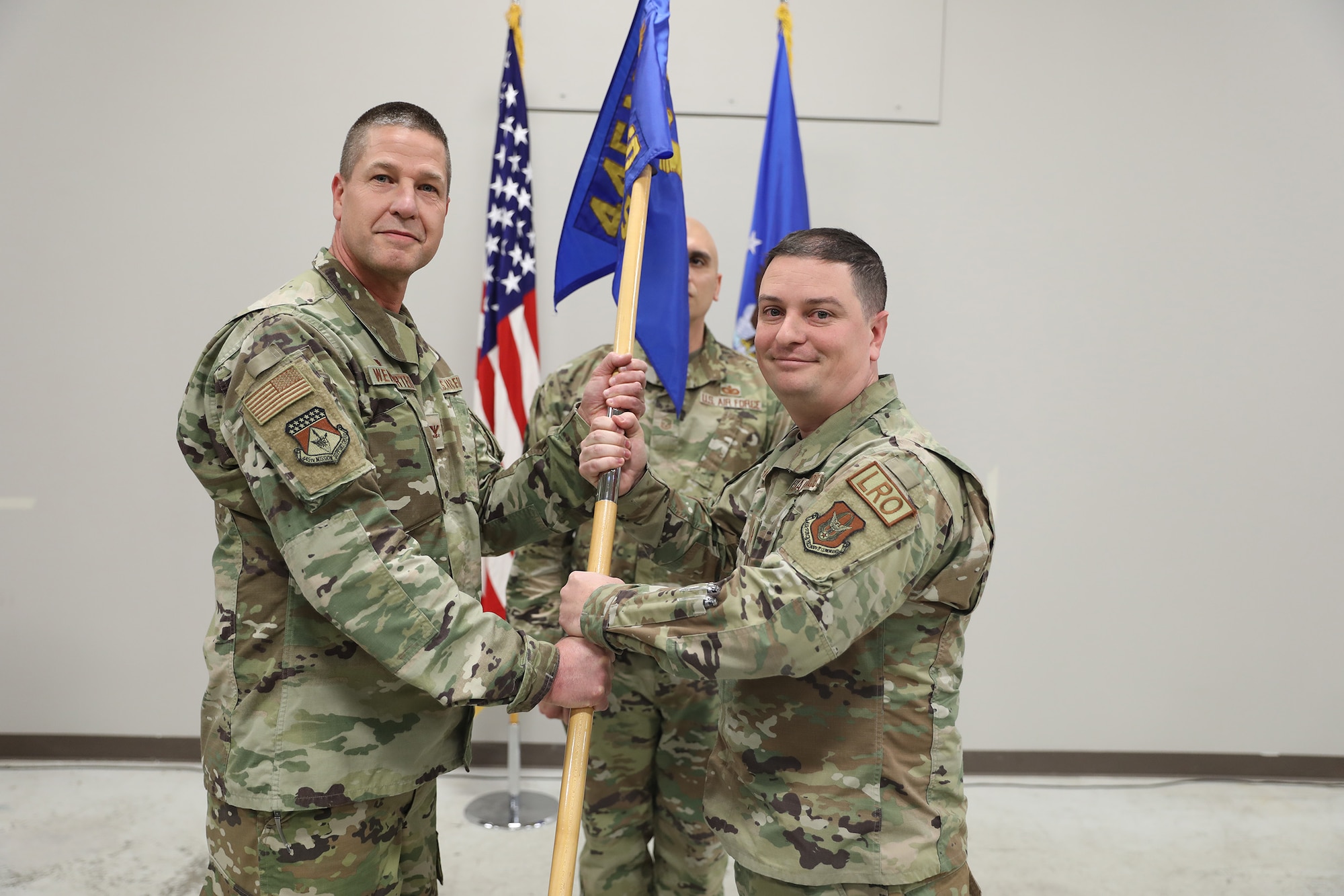 Col. Robert Wengerter, 445th Mission Support Group commander, passes the guidon to the incoming 445th Logistics Readiness Squadron commander, Maj. William Harris, during an assumption of command ceremony Dec. 7, 2024 held in the Civil Engineer Bay of Bldg. 101.