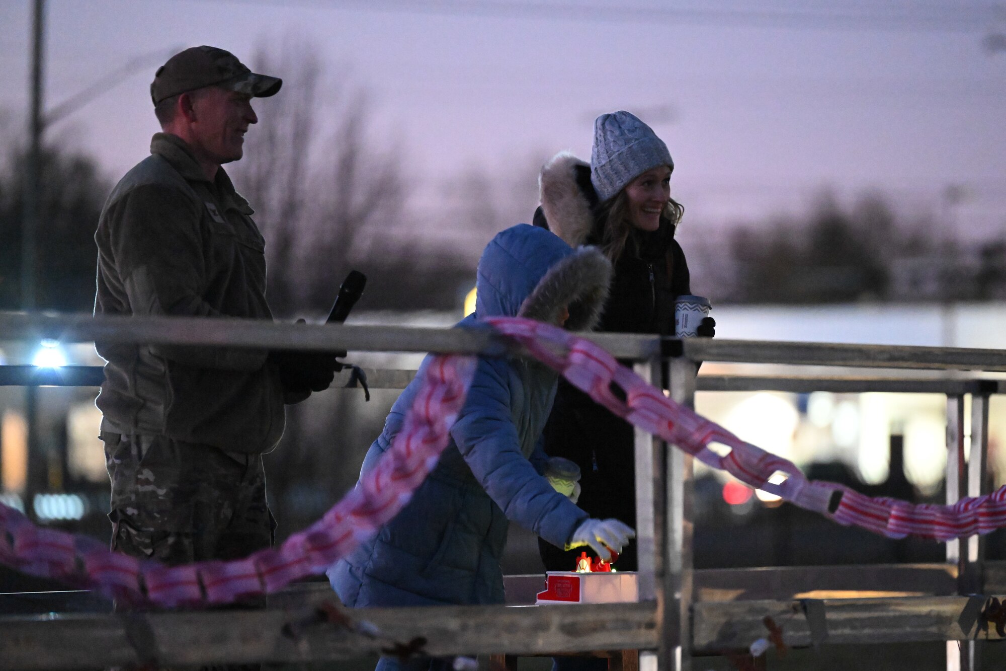 From left, U.S. Air Force Col. Ryan G. Walinski, 316th Wing and installation deputy commander, Skyler Miller, and Jennifer Miller flip the tree lighting switch during the annual Christmas Tree and Menorah Lighting ceremony at Joint Base Andrews, Md., Dec. 5, 2024. Skyler was chosen in recognition of her family’s service and sacrifice while one of her parents is deployed during the holidays.