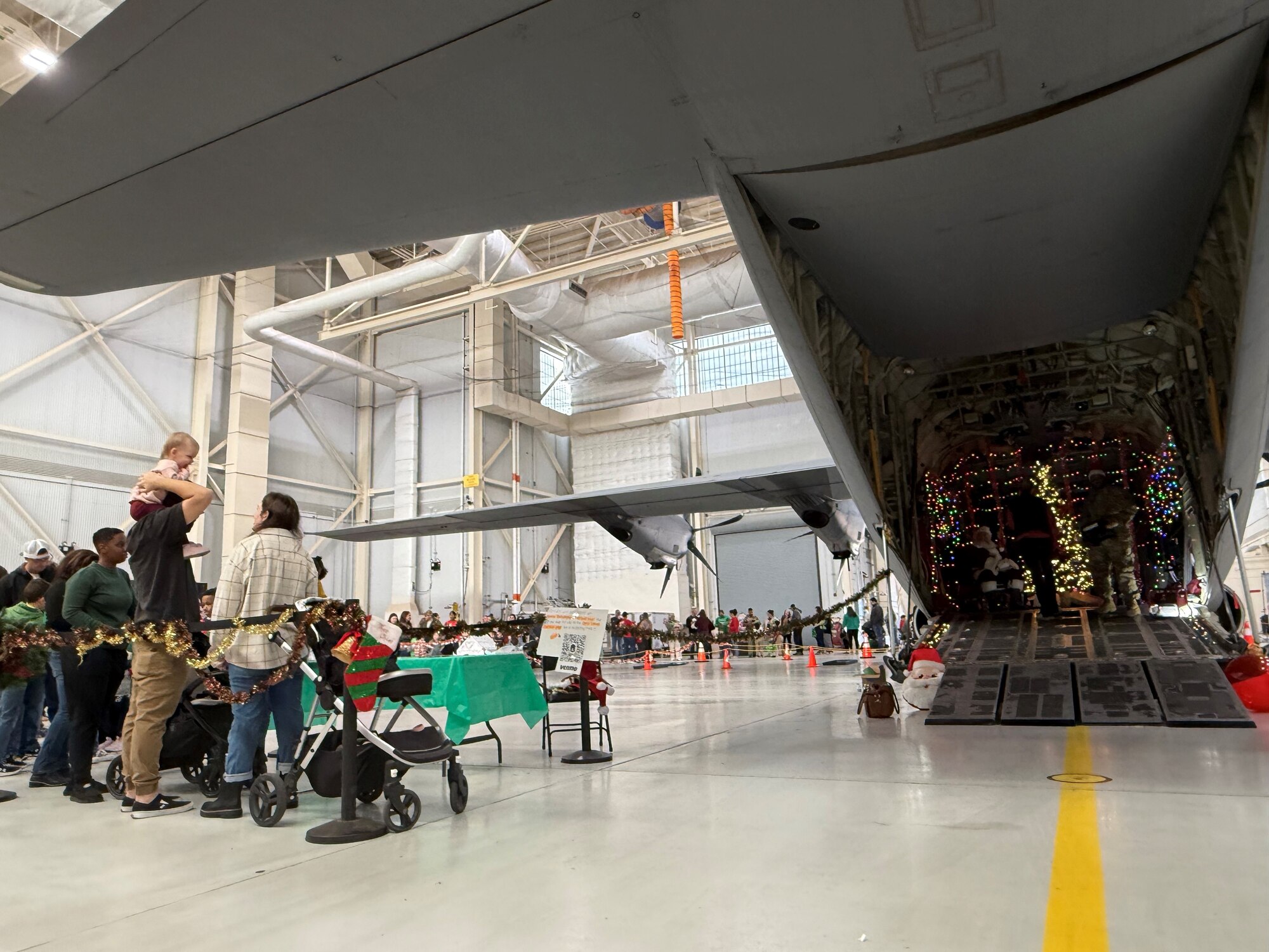 Airmen from the 317th Airlift Wing and their families wait in line to meet and take photos with Santa at the Santa on a Herc event on Dyess Air Force Base, Texas, Dec. 8, 2024. The wing has hosted the event for over 10 years to give Airmen a chance to relax and enjoy holiday festivities with their families. (U.S. Air Force photo by Staff Sgt. Holly Cook)