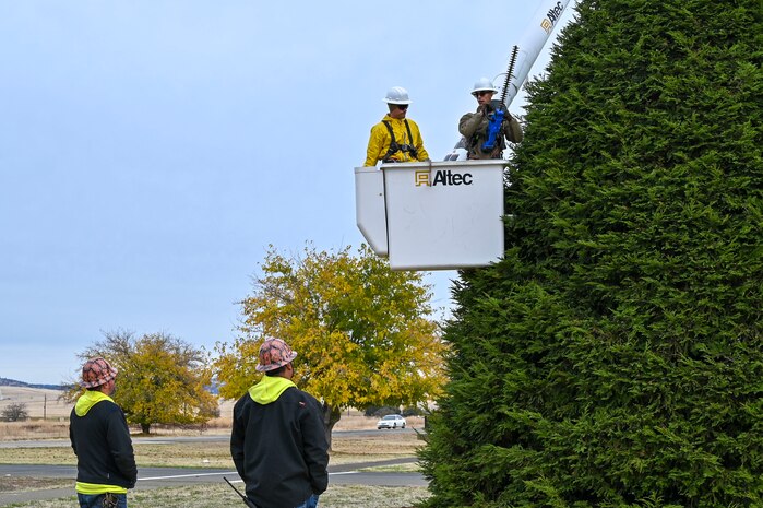 Michael Davis and Gregory Stackhouse, 9th Civil Engineer Squadron (CES) high voltage electricians, guide U.S. Air Force Senior Airman Timofei Sennikov and Airman Elijah Perry, 9th Civil Engineer Squadron electrical systems journeymen, as they trim the Beale Christmas tree from the bucket of a truck on Beale Air Force Base, California, Nov. 18, 2024.
