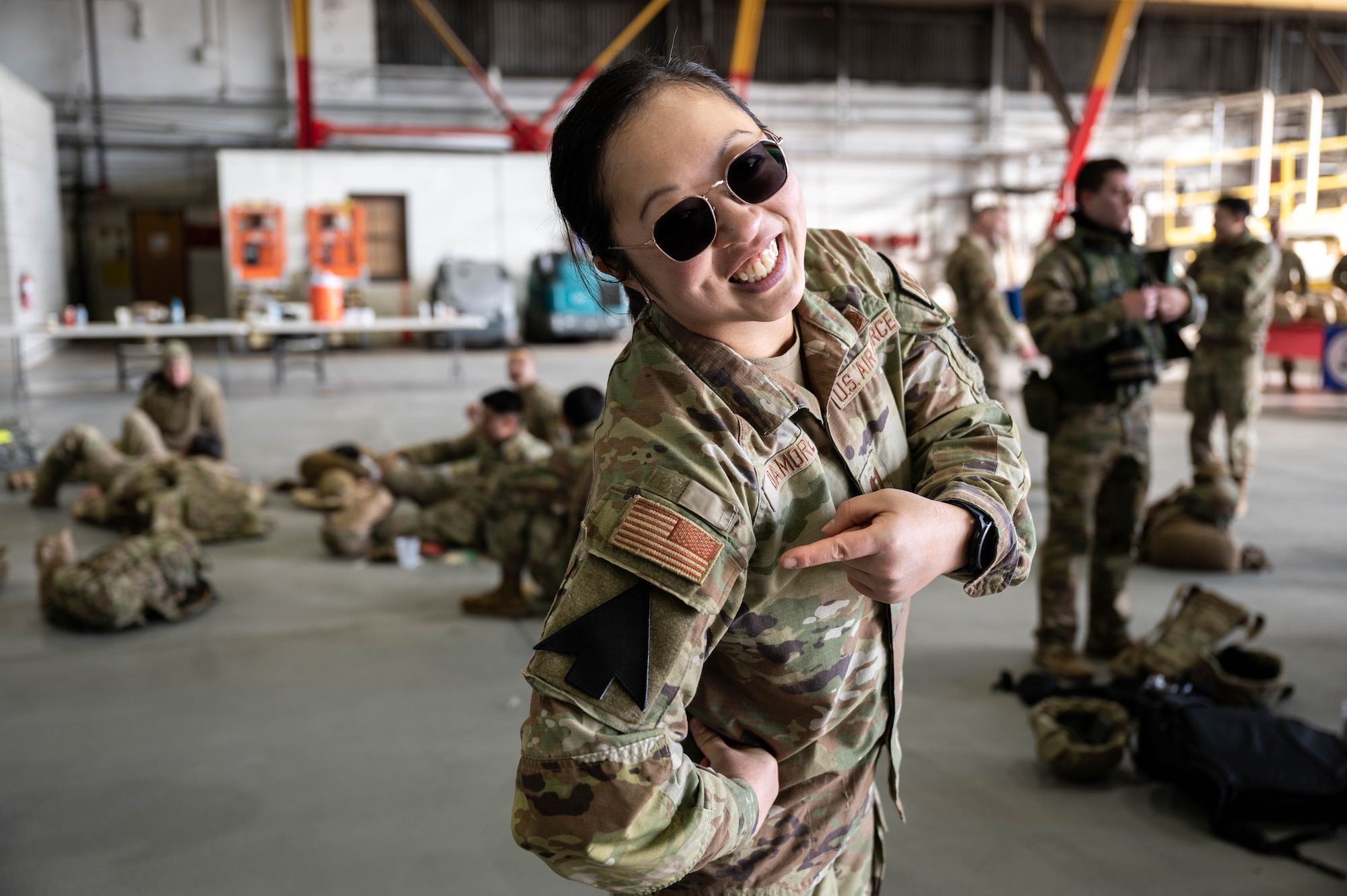 An Air Force captain smiles and points to her black arrow patch on her arm.